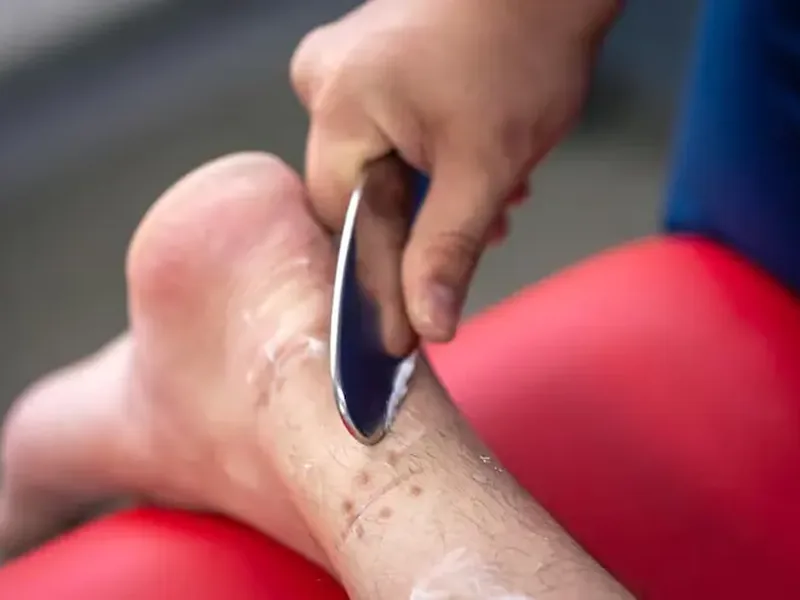 Dr. Moy using an IASTM tool along a patient&rsquo;s calf at Amplify Physical Therapy and Wellness in Bolingbrook