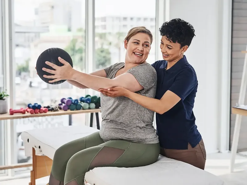 Dr. Moy coaching a patient through a strengthening exercise during a one-on-one physical therapy visit in Bolingbrook