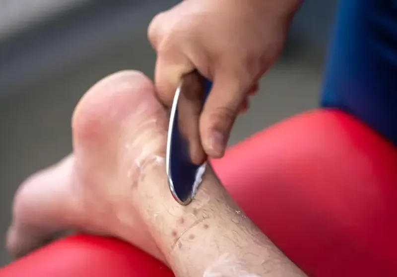Clinician using an instrument-assisted soft tissue tool on a patient&rsquo;s calf